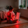 Vrouw zit in kleermakerszit op de slaapkamervloer voor de ATP Pure 700, rood licht aan